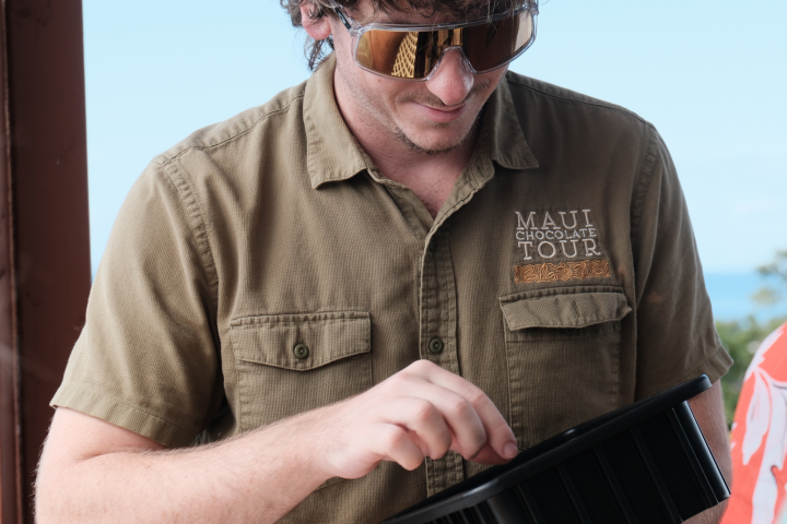 Person wearing sunglasses inspects item from a black container.