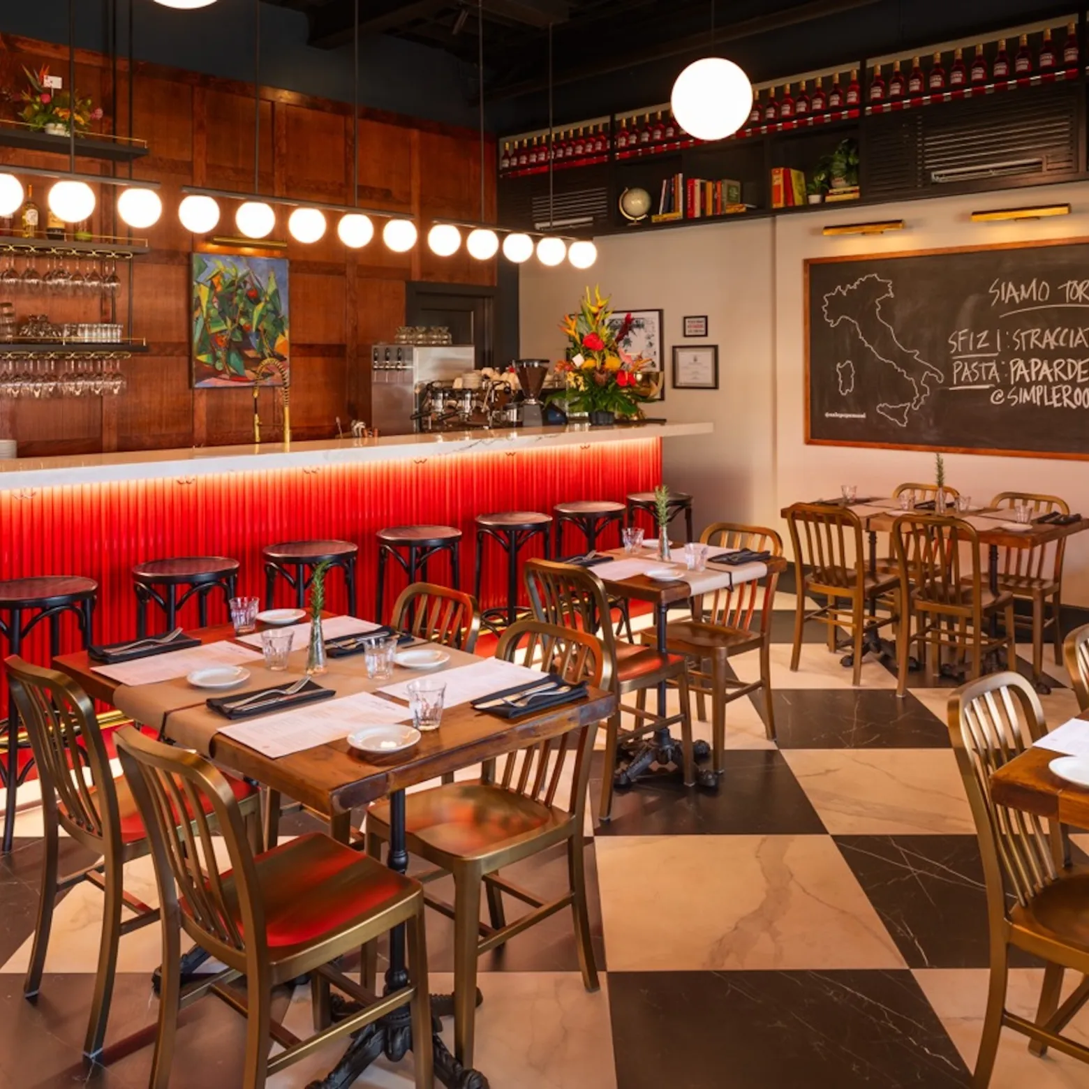 Cozy Italian restaurant interior with red-lit bar, wooden tables, and chalkboard menu.